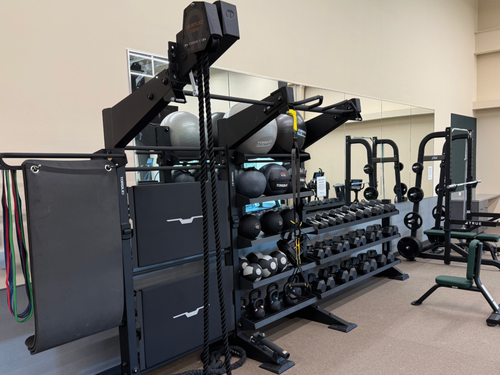 A neatly arranged gym space with functional training gear, dumbbells, and resistance tools from Torque and TRUE. The photo highlights the results of consistent maintenance and inspection — a clean, efficient, and high-performing fitness environment for users.