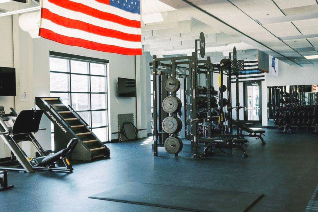 Commercial strength training room with maintained fitness equipment and American flag overhead.