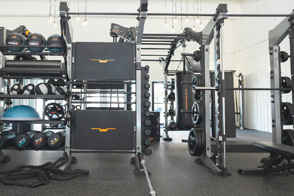 Organized commercial gym with functional training equipment and free weights.