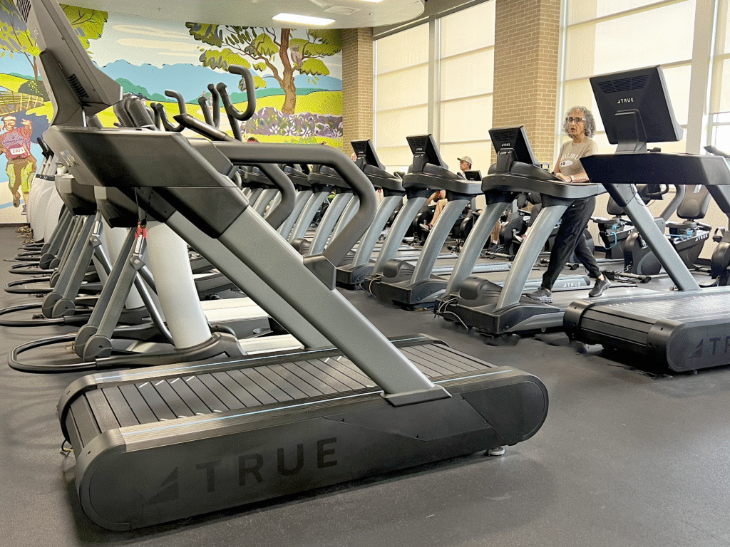 Fitness center with TRUE treadmills and cardio equipment in use.