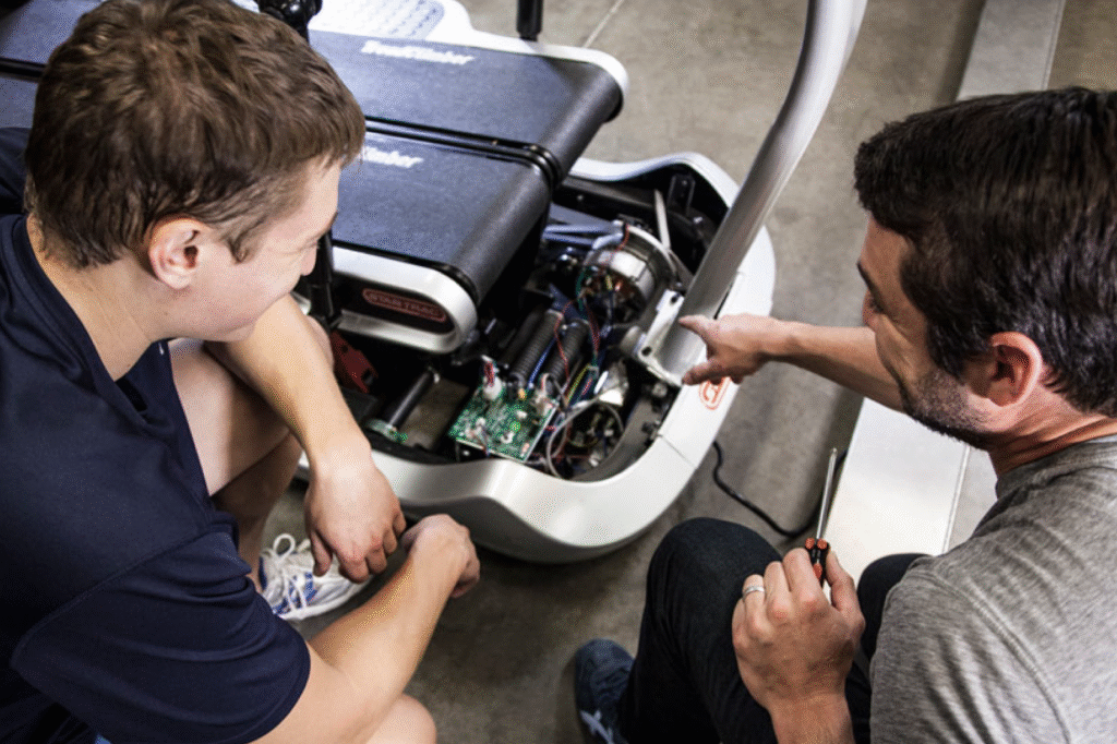technician performing preventative maintenance on commercial fitness equipment in a gym