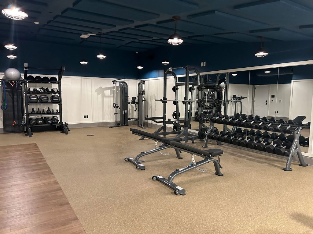 Well-equipped gym with benches, dumbbells, and cable machines requiring regular maintenance checks.