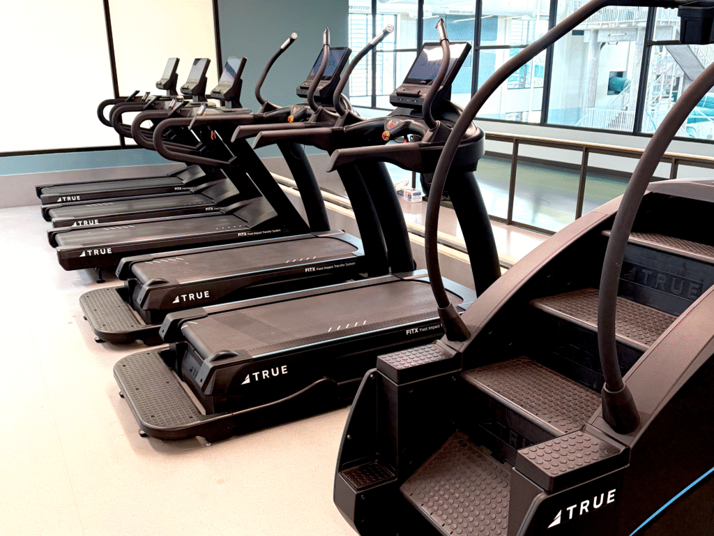 Row of commercial treadmills and stair machines maintained through preventative care to extend equipment lifespan.