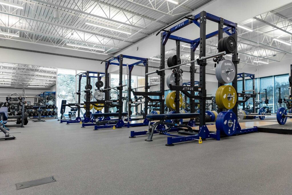 TRUE Fitness racks and weightlifting platforms in a modern commercial gym.