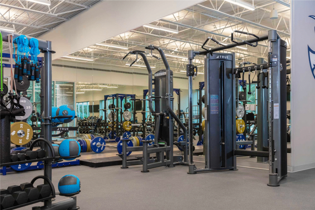 Modern commercial gym with functional trainers, weights, and well-maintained fitness equipment.