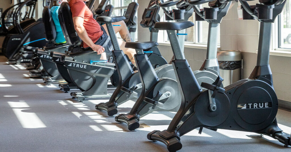 TRUE upright and recumbent bikes in a hotel fitness center with guests using cardio equipment.